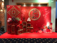 a red stage with flowers and decorations on the floor, in front of a wall