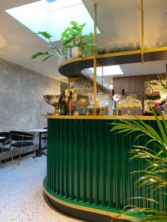 the interior of a restaurant with green walls and plants growing on the bar counter top