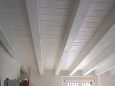 an empty room with white painted ceilings and wood floors