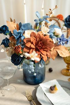 a blue vase filled with flowers on top of a table next to a white plate