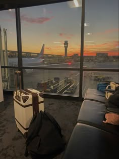 an airport terminal with luggage on the ground and planes in the background at sunset or dawn