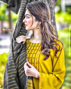 a woman in yellow is holding an umbrella and posing for the camera with her hand on her shoulder