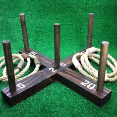 three wooden poles with ropes on top of them sitting in the middle of green grass