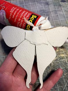 someone is holding an origami angel with glue on it's wings and the paper has been cut out