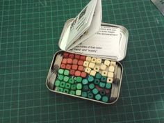 an open tin with some sort of colored dices in it on a green table