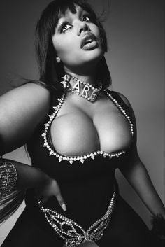 a woman in a bodysuit with chains around her neck and chest, posing for the camera