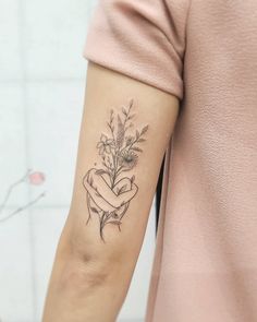 a woman with a tattoo on her arm holding a flower in the shape of a heart