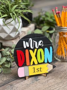 a wooden sign that says we are dixon next to some pens and pencils