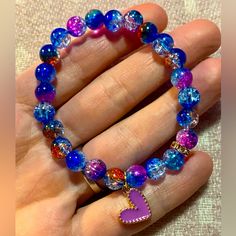 a woman's hand holding a bracelet with purple beads and a pink heart charm