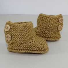 a pair of crocheted baby booties with buttons on the front and bottom