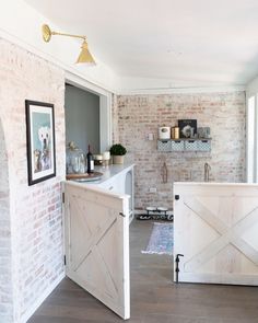 a kitchen with brick walls and wooden doors on the wall, along with an open door leading to another room