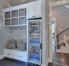 an open refrigerator in a kitchen next to some drawers and shelves with drinks on them