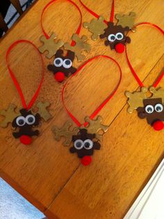 four christmas ornaments made to look like reindeers with red noses and brown eyes on a wooden table