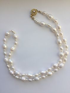 "This beautiful necklace is fashioned from white freshwater pearls; the largest measures approximate 8x10 mm; accented by a smaller 5.5-6 mm pearl and then small white 3mm pearls.  The necklace is 25\" long, a beautiful matinee length and is knotted for security.  It fastens with a goldtone pearl-set clasp in the shape of a flower." Classic Double Strand Pearl Pendant Necklace, Classic Double Strand Pearl Necklace With Pendant, Classic Pearl Necklace With Baroque Pearl Chain, Classic Baroque Pearl Necklace With Pearl Chain, Oval Pearl Pendant Necklace In Pearl White, Oval Pearl White Necklace With Pearl Pendant, Classic Pear-shaped Pearl Necklace With Charm, Classic Pear-shaped Pearl Necklace, Double Strand Pearl White Necklace With Pearl Pendant