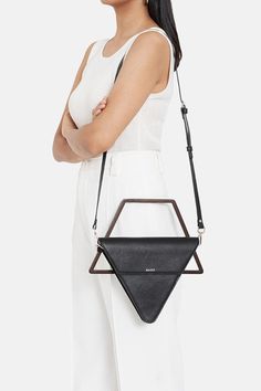 Black geometric balanced triangular bag with  removable wooden handle and a crossbody with a detachable leather strap.
Components: 1 Bag, 1 Wooden Handle, 1 Detachable Leather Strap
Composition: Leather and Wooden Handle
Color: Black
Other Details: 
Dimensions: L x B x W (in cms): 21 x 4.5 x 25
Product weight (in gms): 500
Disclaimer: Leather is a natural material. Hence, it is possible for colour variations and markings to appear in the leather. These should not be thought of as defects or impe Geometric Bag Design, Easy Rangoli Designs Videos, Diy Projects To Make And Sell, Triangle Bag, Unique Handbag, Unique Handbags, Stylish Purse, Luxury Purses, Chic Handbags