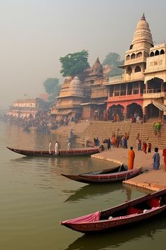 several boats docked at the edge of a body of water in front of a building