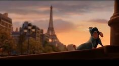 a cartoon mouse sitting on top of a ledge in front of the eiffel tower