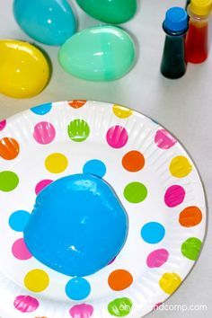 a paper plate with colorful polka dots on it next to markers and paint bottles in the background