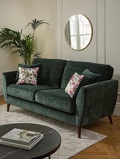 a living room filled with furniture and a round mirror on the wall over a coffee table