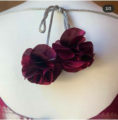 two flowers are attached to a necklace on a mannequin