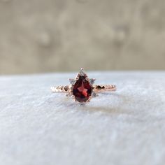 a close up of a ring with a red stone in it on a white surface