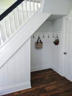 there is a white staircase with hooks on the wall and two bags hanging up against the banister