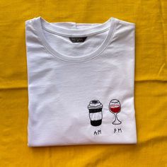 a white t - shirt with two glasses of wine on it