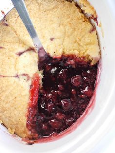 a piece of pie is being cut into with a large knife in it's bowl