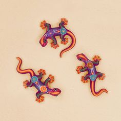 three colorful geckos sitting on top of a white wall next to each other