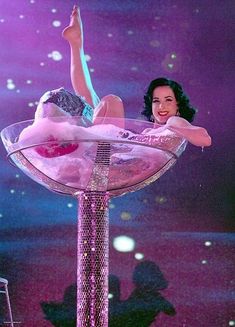 a woman in pink dress sitting on top of a glass bowl with water and stars