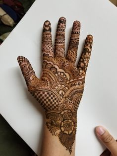 a hand with henna on it is shown in front of a piece of paper