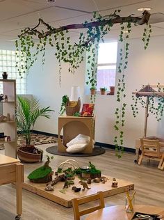 a room filled with lots of wooden tables and chairs covered in green ivys hanging from the ceiling