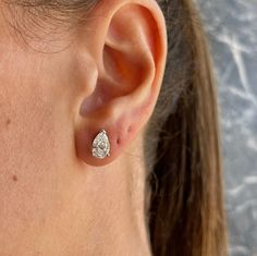 a close up of a person wearing a pair of ear studs with a diamond in the middle