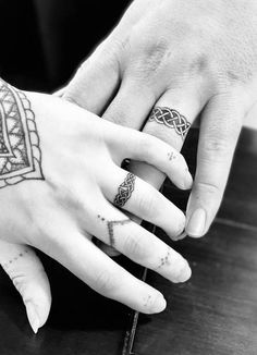 two people with tattoos on their hands holding each other's hand and touching the finger