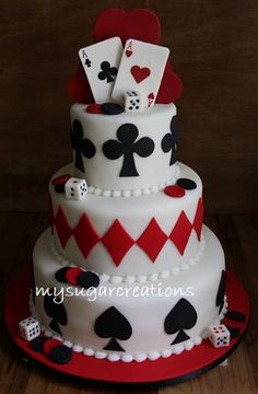 a three tiered cake with playing cards and dice on the top, sitting on a wooden table