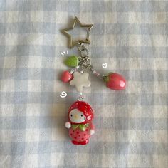 a hello kitty keychain hanging from a star shaped object on a checkered table cloth