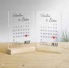 two clear acrylic calendars with hearts on them sitting on a wooden table