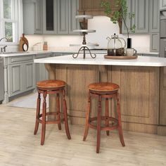 two wooden stools sit at the center of a kitchen island