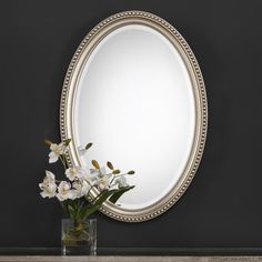 a vase filled with flowers sitting next to a mirror on top of a wooden table