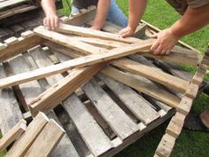 two men working on some wooden boards in the grass