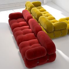 three different colored couches sitting next to each other on a white floor in an empty room