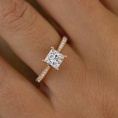 a woman's hand with a diamond engagement ring on her finger and the center stone is