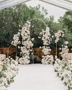 an outdoor ceremony with white flowers and greenery