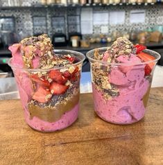 two desserts in plastic cups with strawberries on top