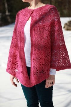 a woman standing in the snow wearing a pink crocheted shawl