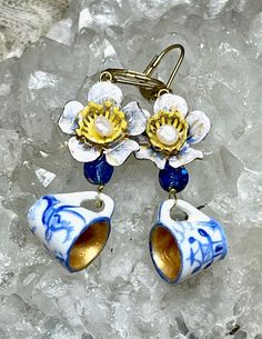 two blue and white flower shaped earrings sitting on top of some ice flaker