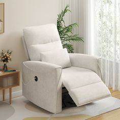 a white recliner chair sitting on top of a hard wood floor next to a window