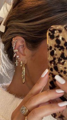 a woman is taking a selfie with her cell phone while wearing gold ear rings