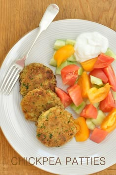 a white plate topped with chicken patties and veggies next to a fork