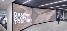 an office lobby with a large screen on the wall that says drawing people together